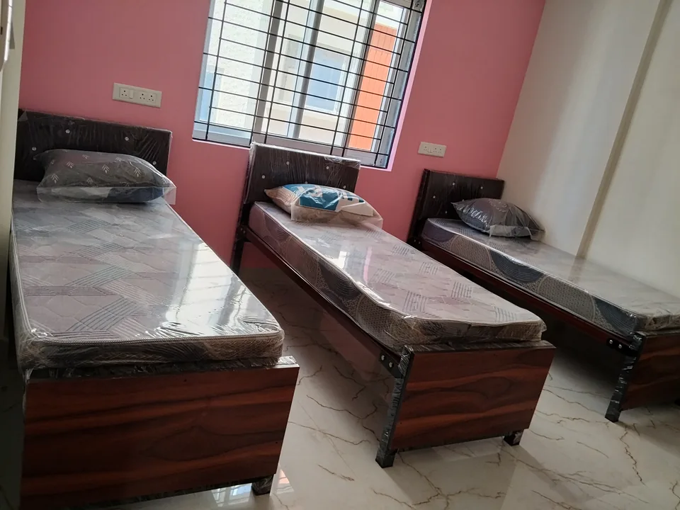 Three beds arranged beneath a barred window in a pink and white room.