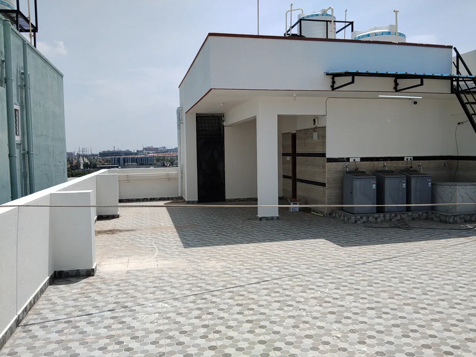 Tiled terrace beside the rooftop utility area under a clear sky.